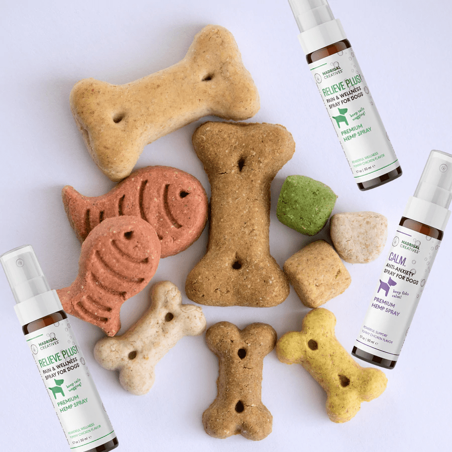 Dog bones of different shapes and sizes and dog hemp CBD spray lying on a white surface.