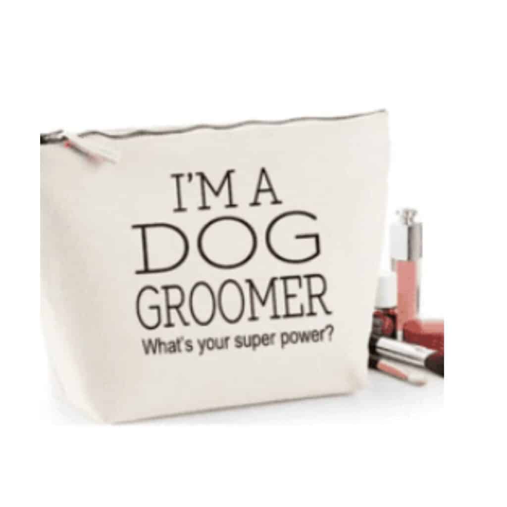 beige canvas bag that says "I am a dog groomer what is your superpower?" beside some cosmetics.