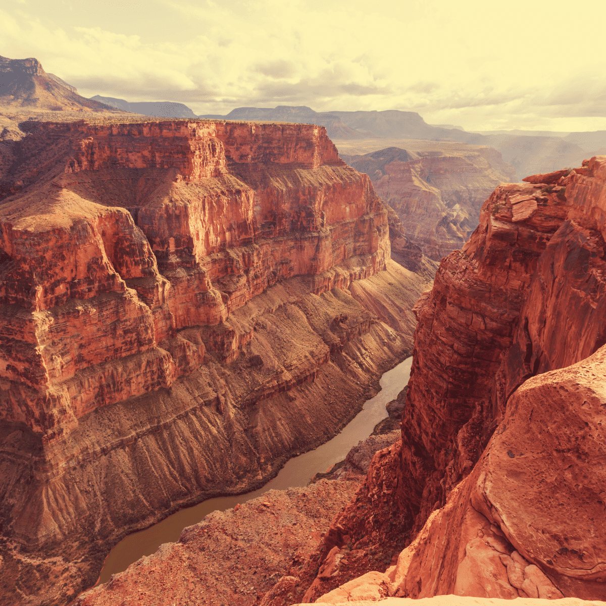 Grand Canyon with steep mountain walls and a river running through the center of the canyon.